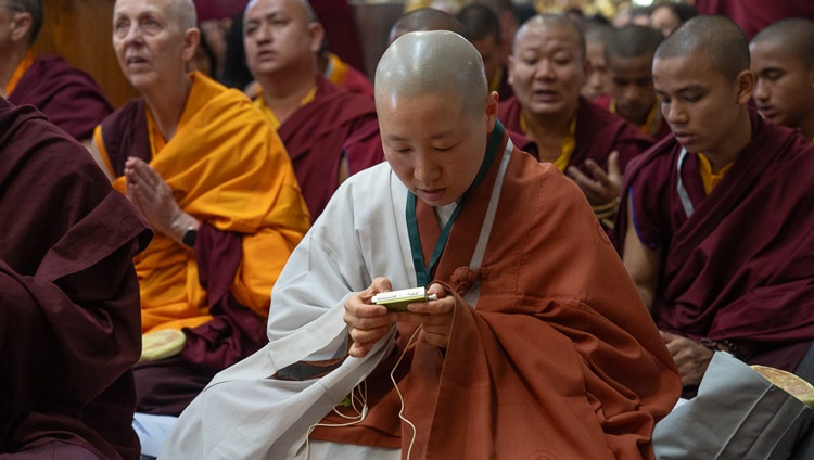 A member of the audience listening to an interpretation of His Holiness the Dalai Lama on FM radio during the Mahakala permission at the Main Tibetan Temple in Dharamsala, HP, India on May 18, 2024. Photo by Tenzin Choejor