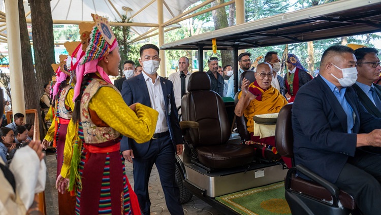 His Holiness the Dalai Lama riding in a golf cart through the courtyard of the Main Tibetan Templ as costumed dancers perform a welcome dance on his way to give the first day of teaching for young Tibetans in Dharamsala, HP, India on June 3, 2024. Photo by Tenzin Choejor